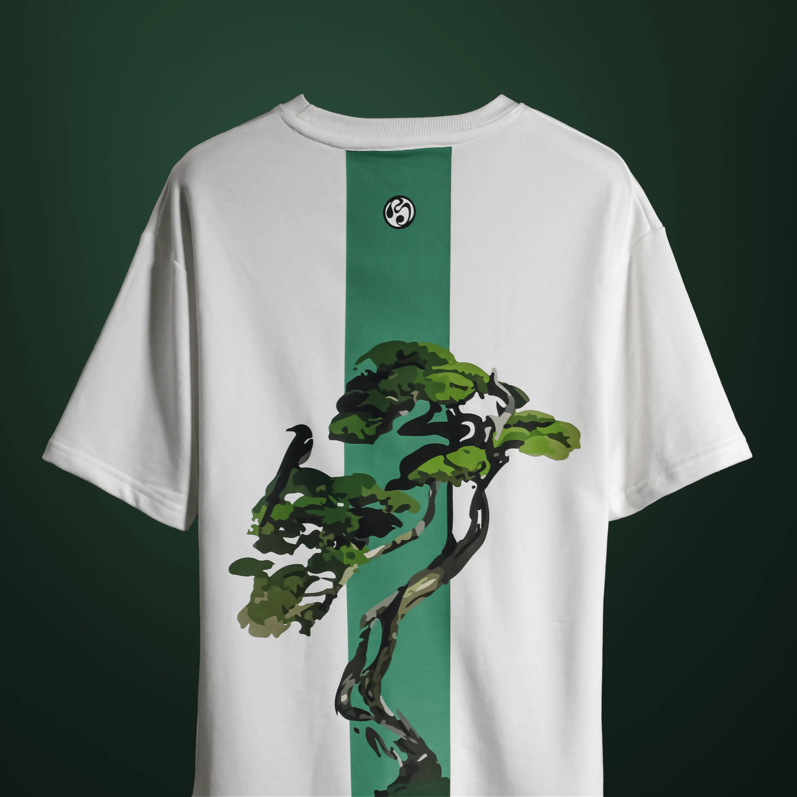 Back view of the Bonsai Tree T-Shirt showing a green vertical stripe with an artistic bonsai tree and crow graphic, printed on white fabric.