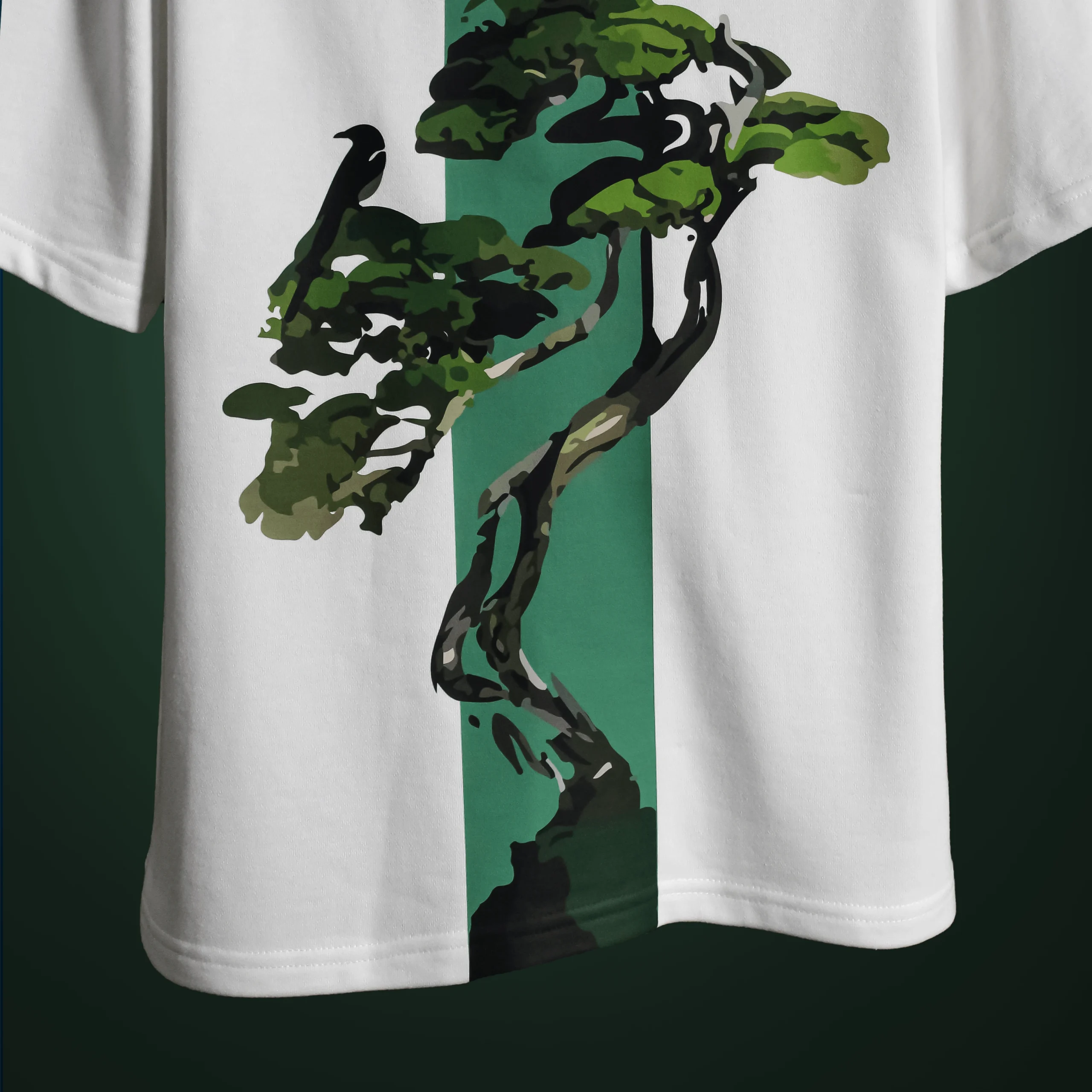Back view of the Bonsai Tree T-Shirt showing a green vertical stripe with an artistic bonsai tree and crow graphic, printed on white fabric.
