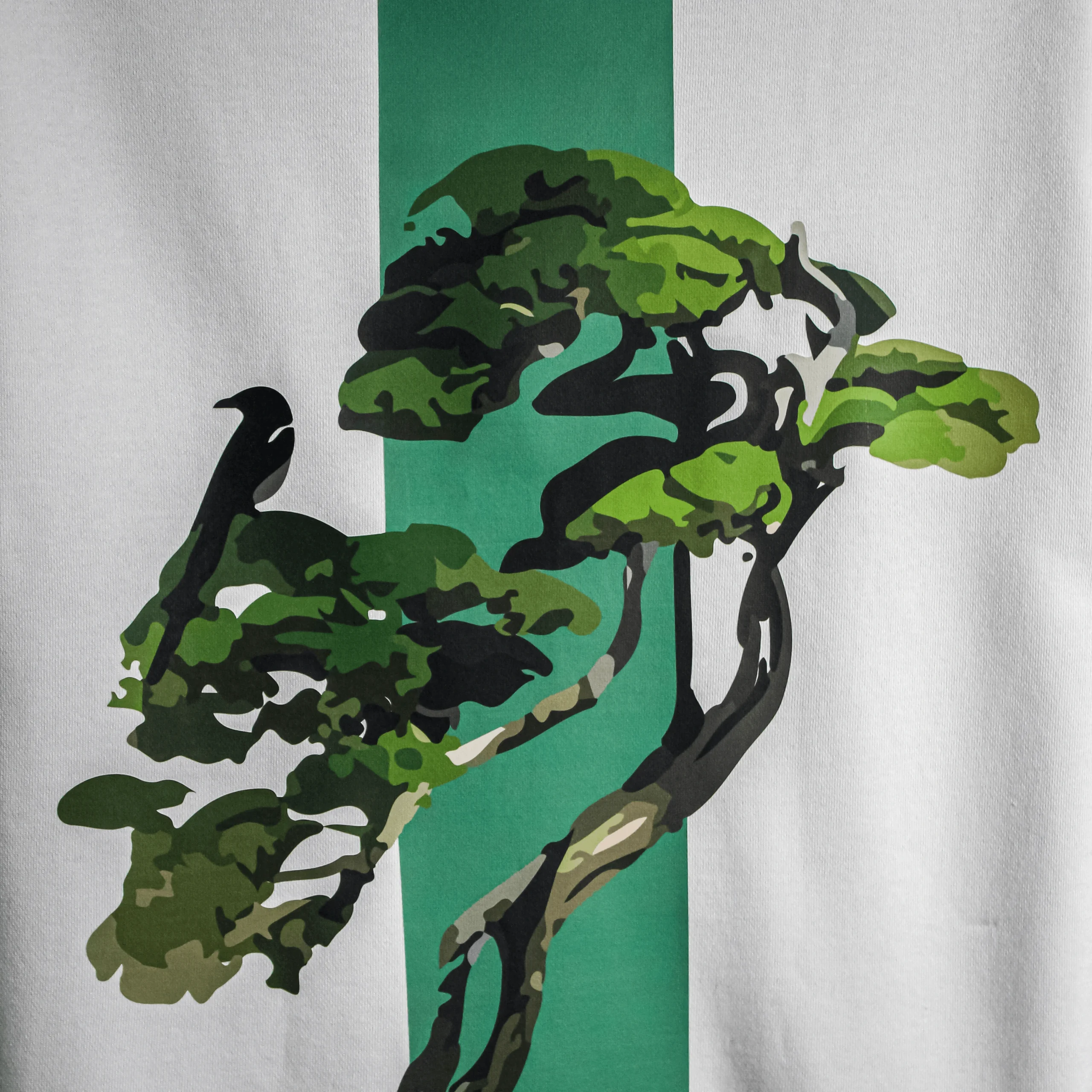 zoomed Back view of the Bonsai Tree T-Shirt showing a green vertical stripe with an artistic bonsai tree and crow graphic, printed on white fabric.